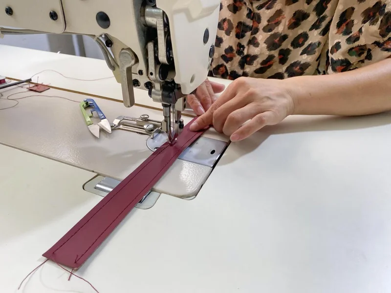 A Gainer craftsperson stitching a leather-covered edge